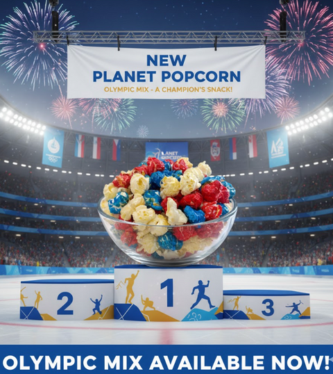 Glass bowl of colorful popcorn with 'New Planet Popcorn' banner and Olympic-themed setting
